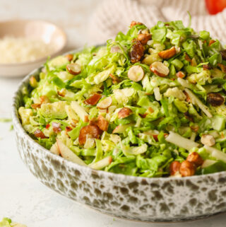 side angle of brussels sprouts salad in a bowl with hazelnuts, dates and apples