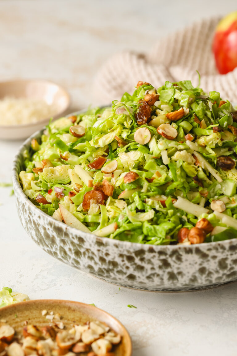 side angle of brussels sprouts salad in a bowl with hazelnuts, dates and apples