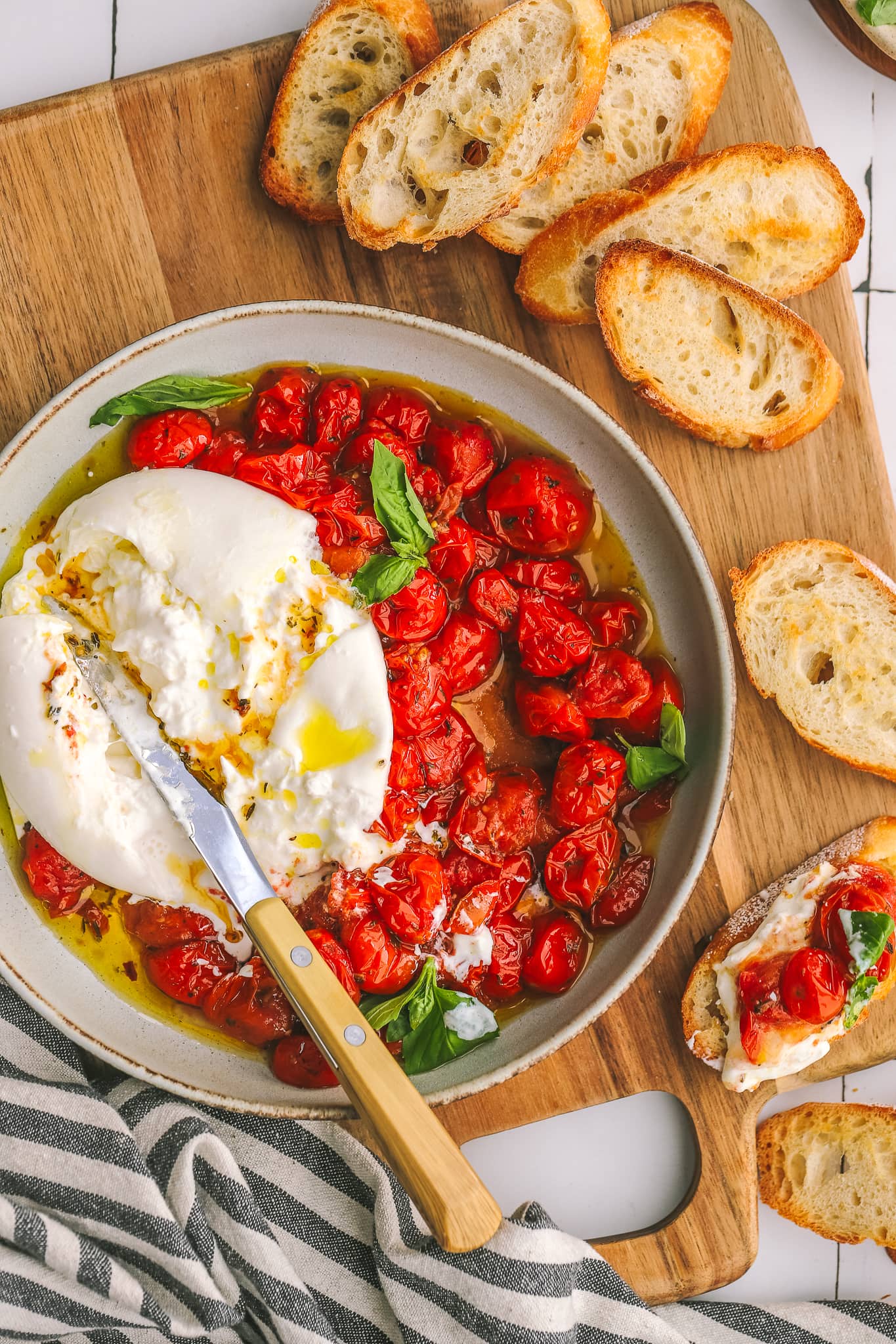 roasted tomatoes in a bowl with burrata cheese and toasted bread