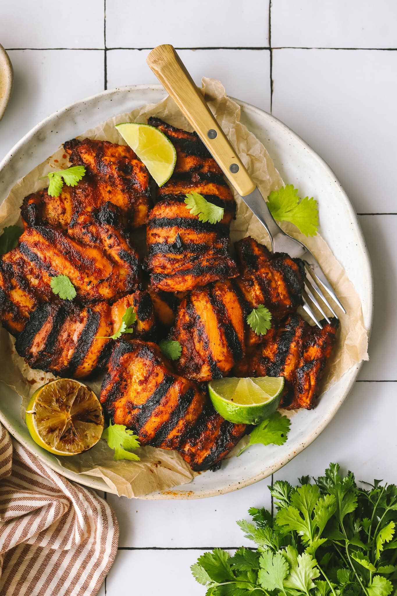 grilled chicken thighs on a plate with limes