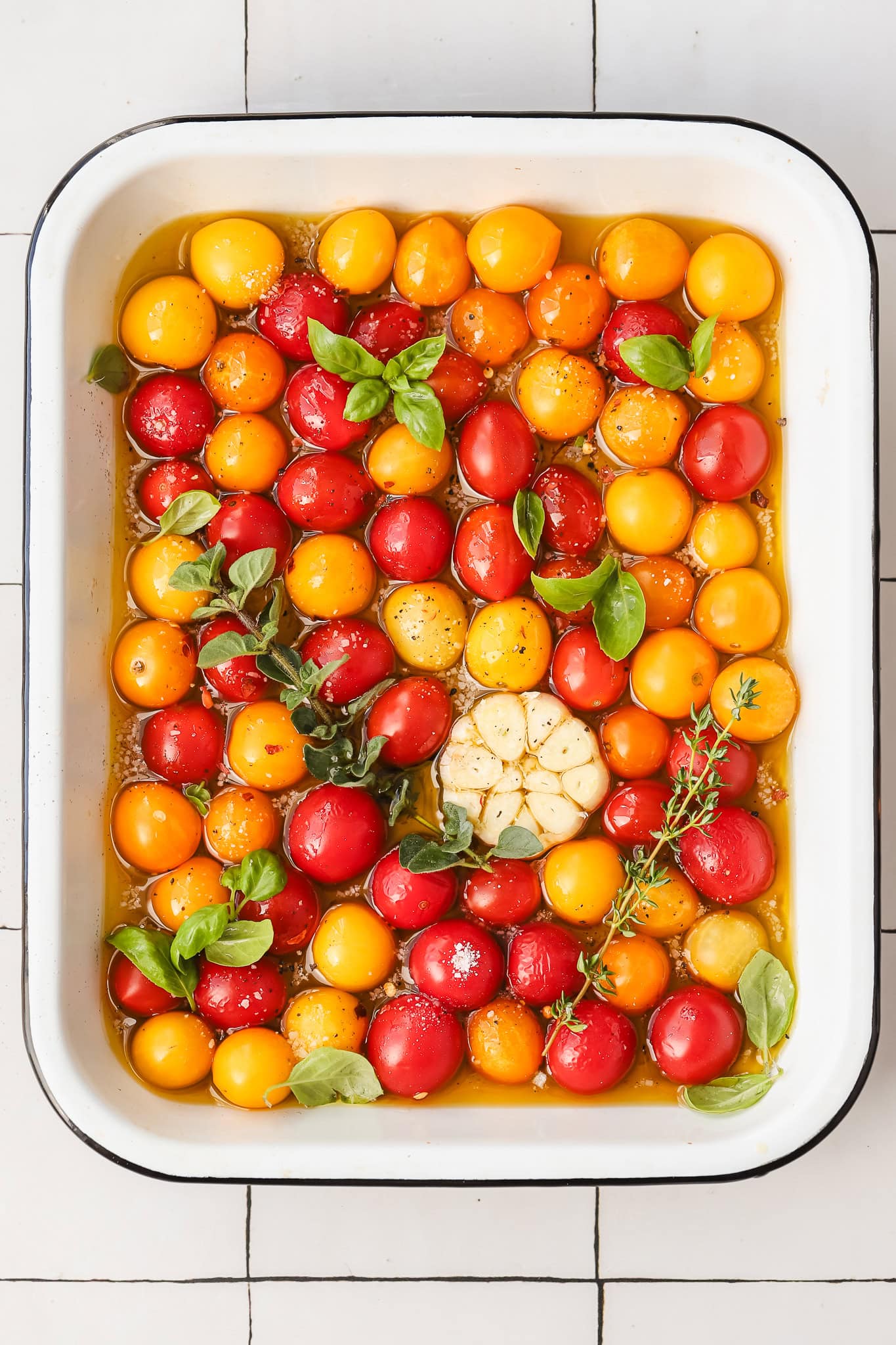 fresh tomatoes in a baking dish with garlic and herbs