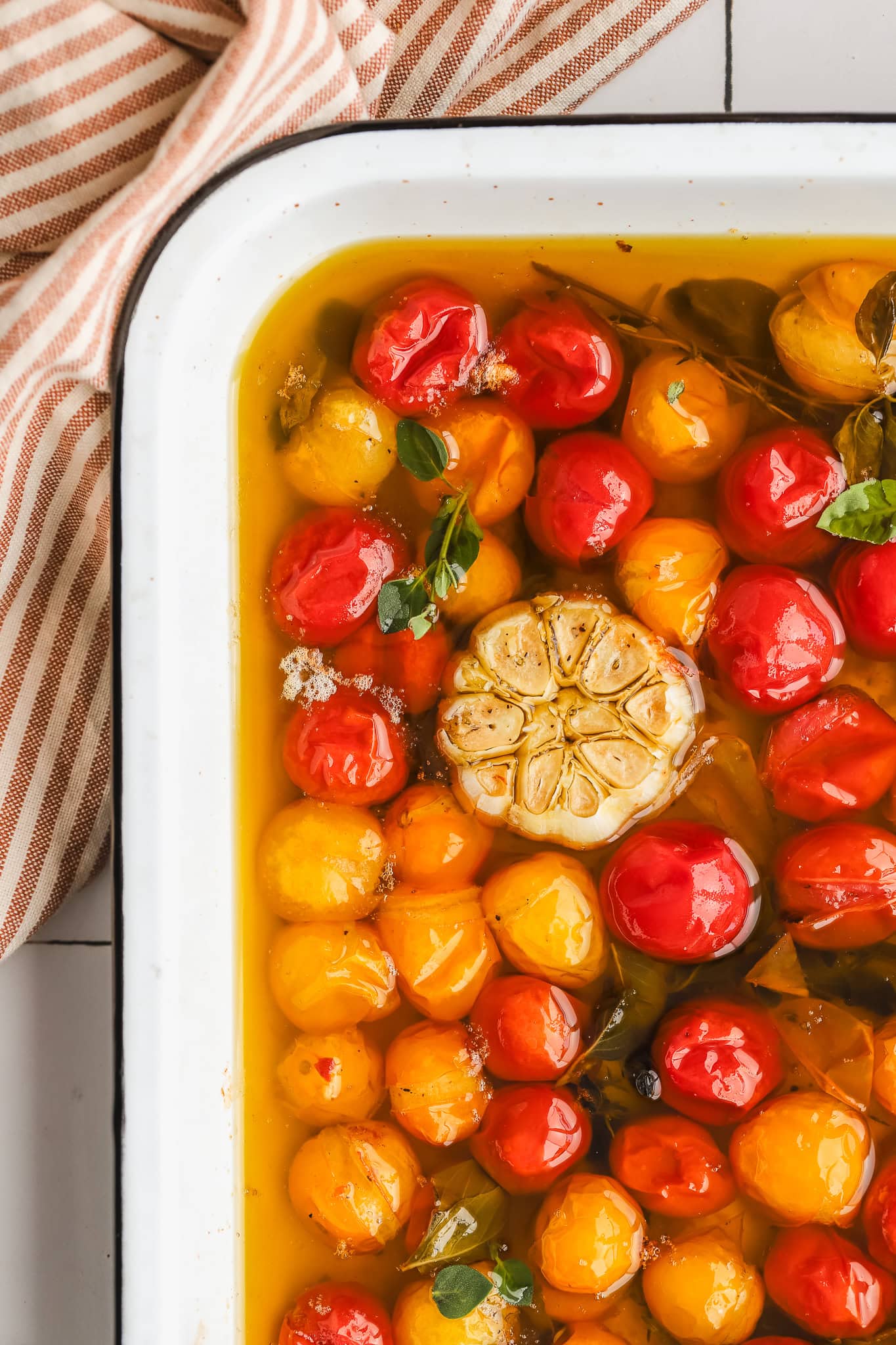 confit tomatoes in a baking dish with garlic and herbs