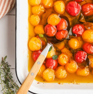 spoon in a baking dish of tomatoes and oil