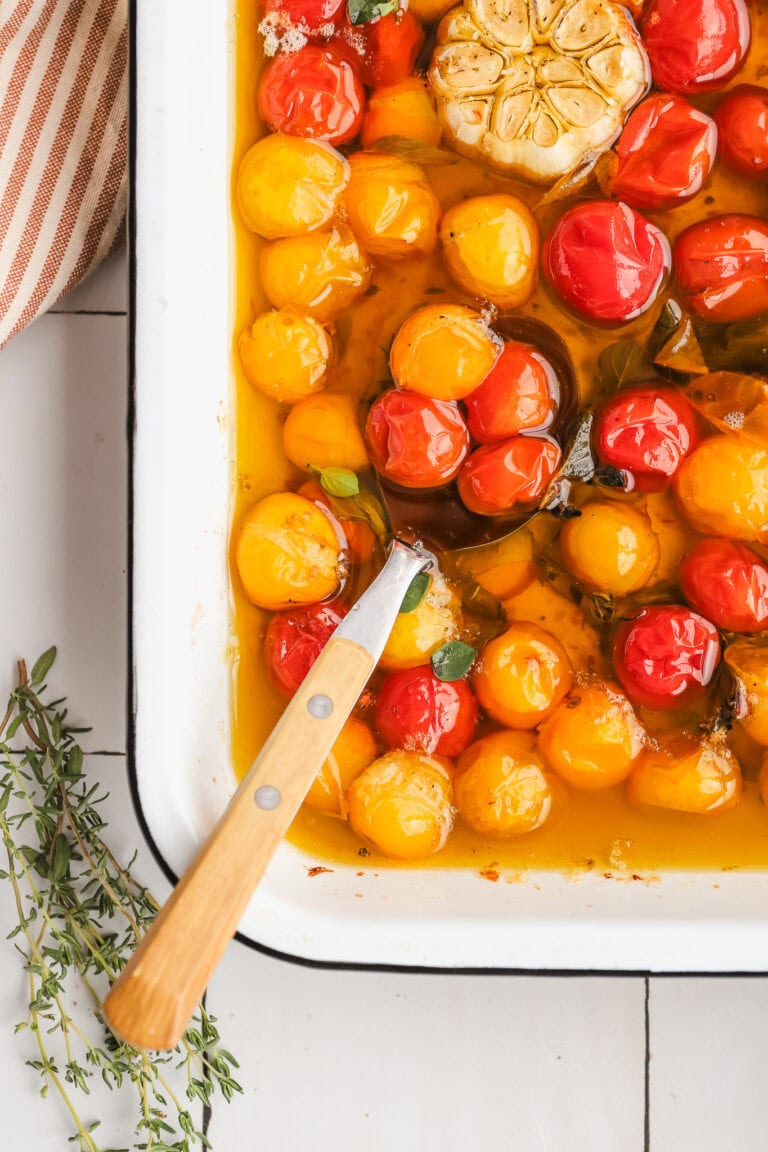 spoon in a baking dish of tomatoes and oil