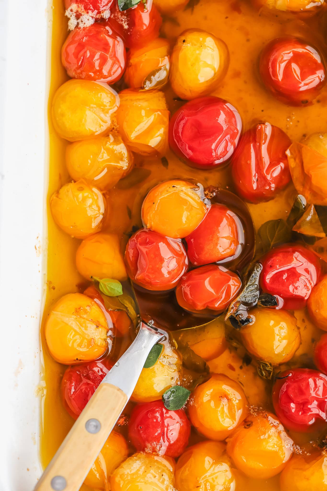 spoon in a baking dish of tomatoes and oil