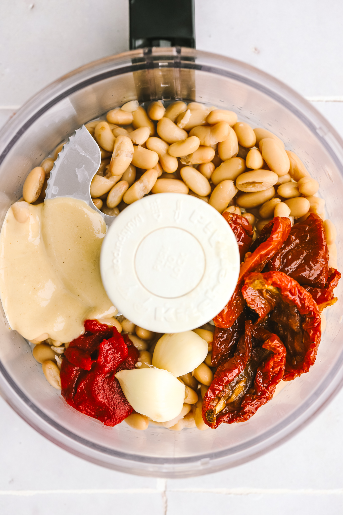 ingredients to make sundried tomato white bean hummus in a food processor