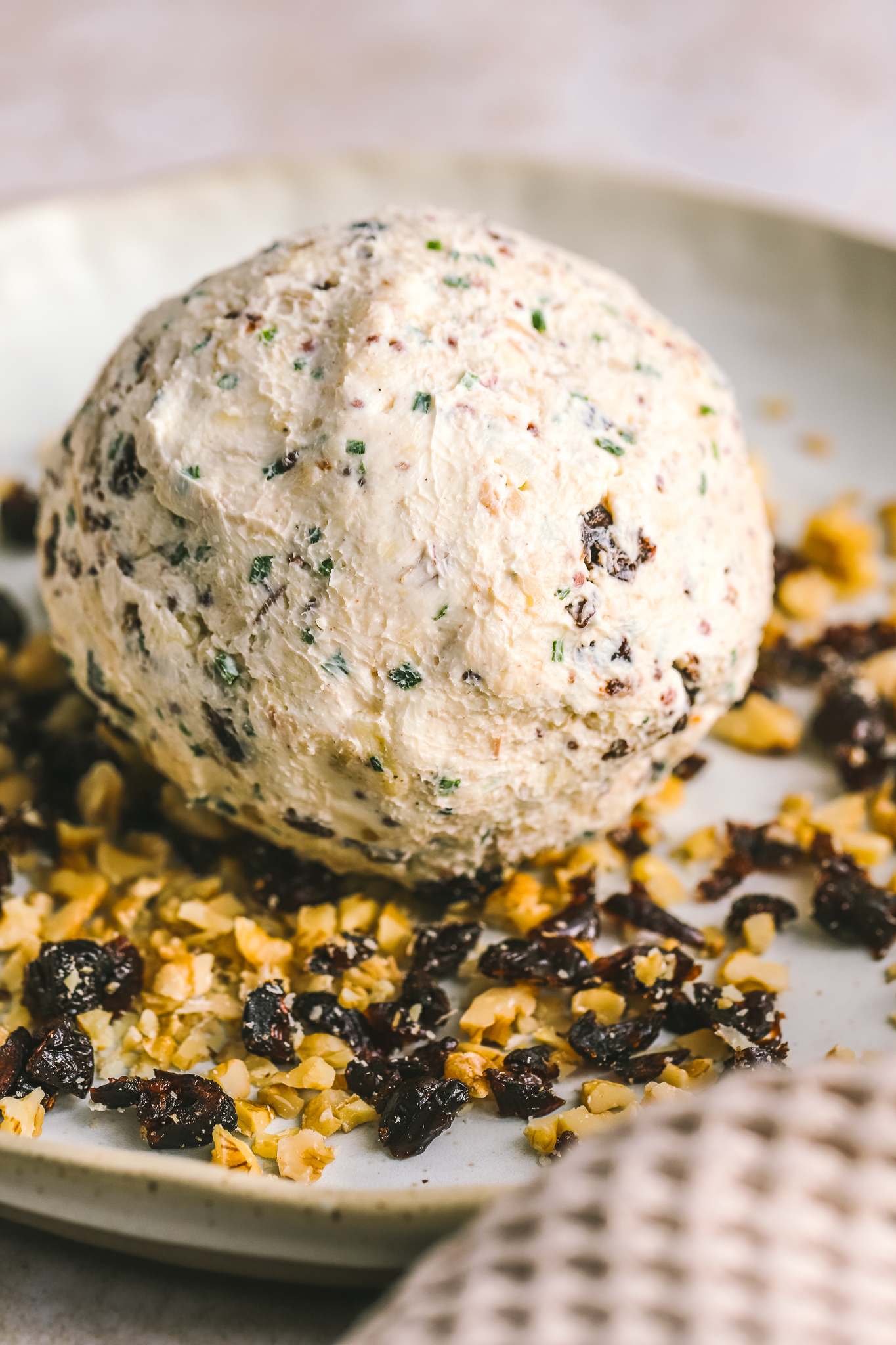 cheese ball being covered in walnuts and dried cranberries