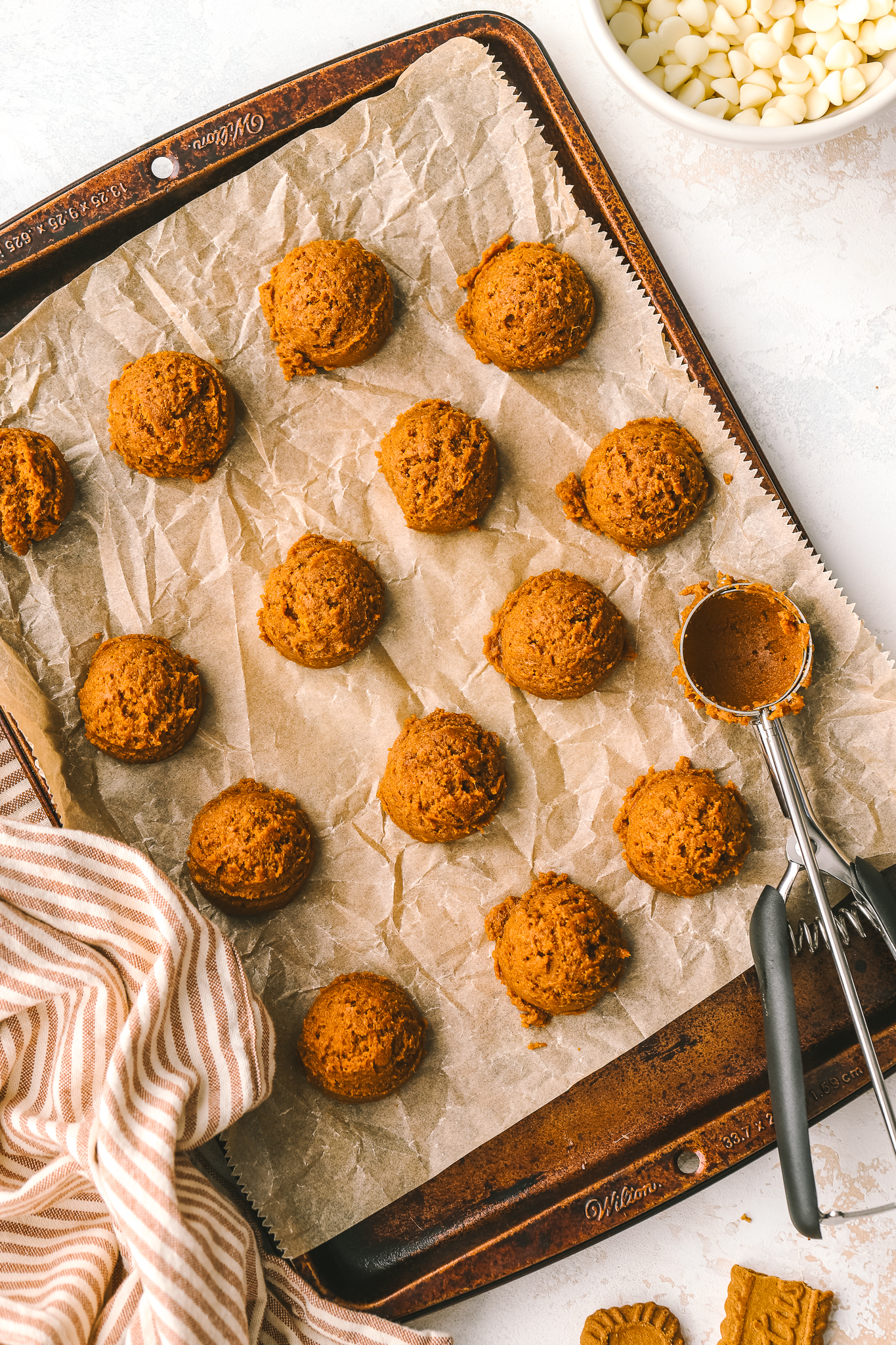 Biscoff pumpkin truffles on a baking sheet with a scoop