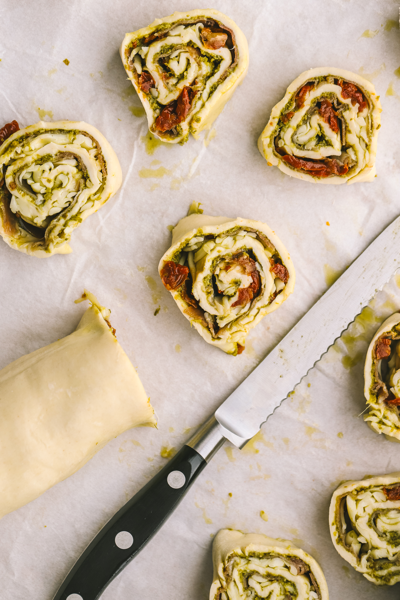pesto pinwheels being cut on a cutting board