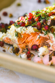 close up of baked salmon with pomegranate seeds, dill and pistachios
