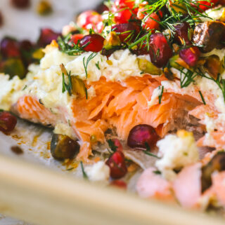 close up of baked salmon with pomegranate seeds, dill and pistachios