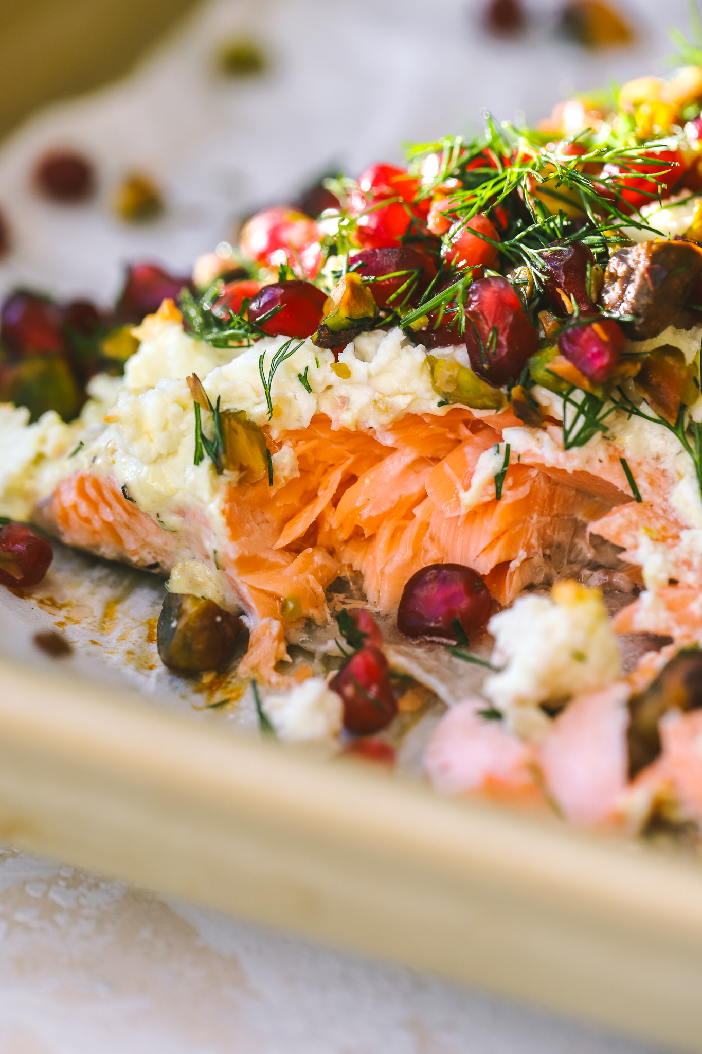 close up of baked salmon with pomegranate seeds, dill and pistachios