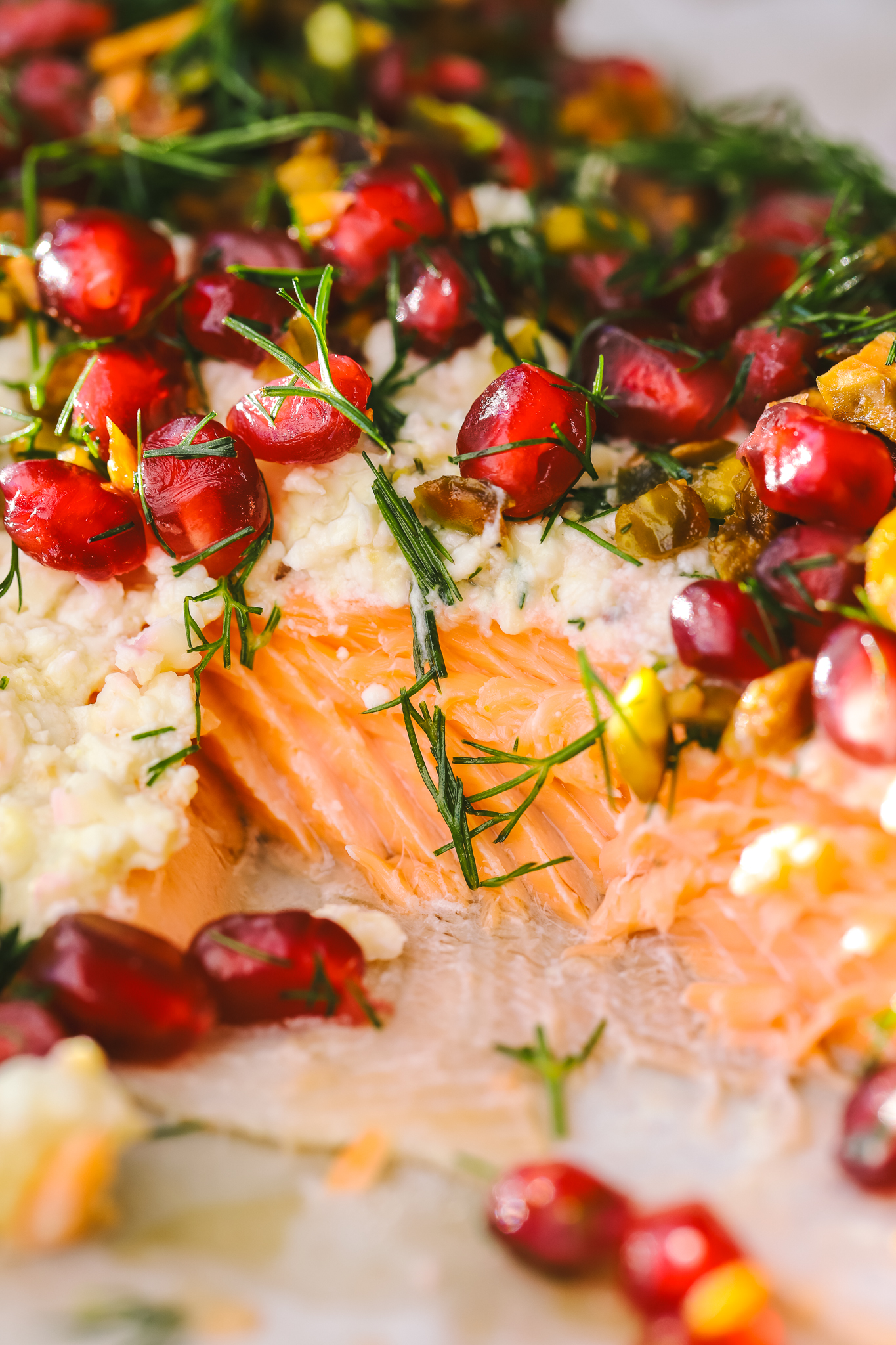 close up of baked salmon with pomegranate seeds, dill and pistachios