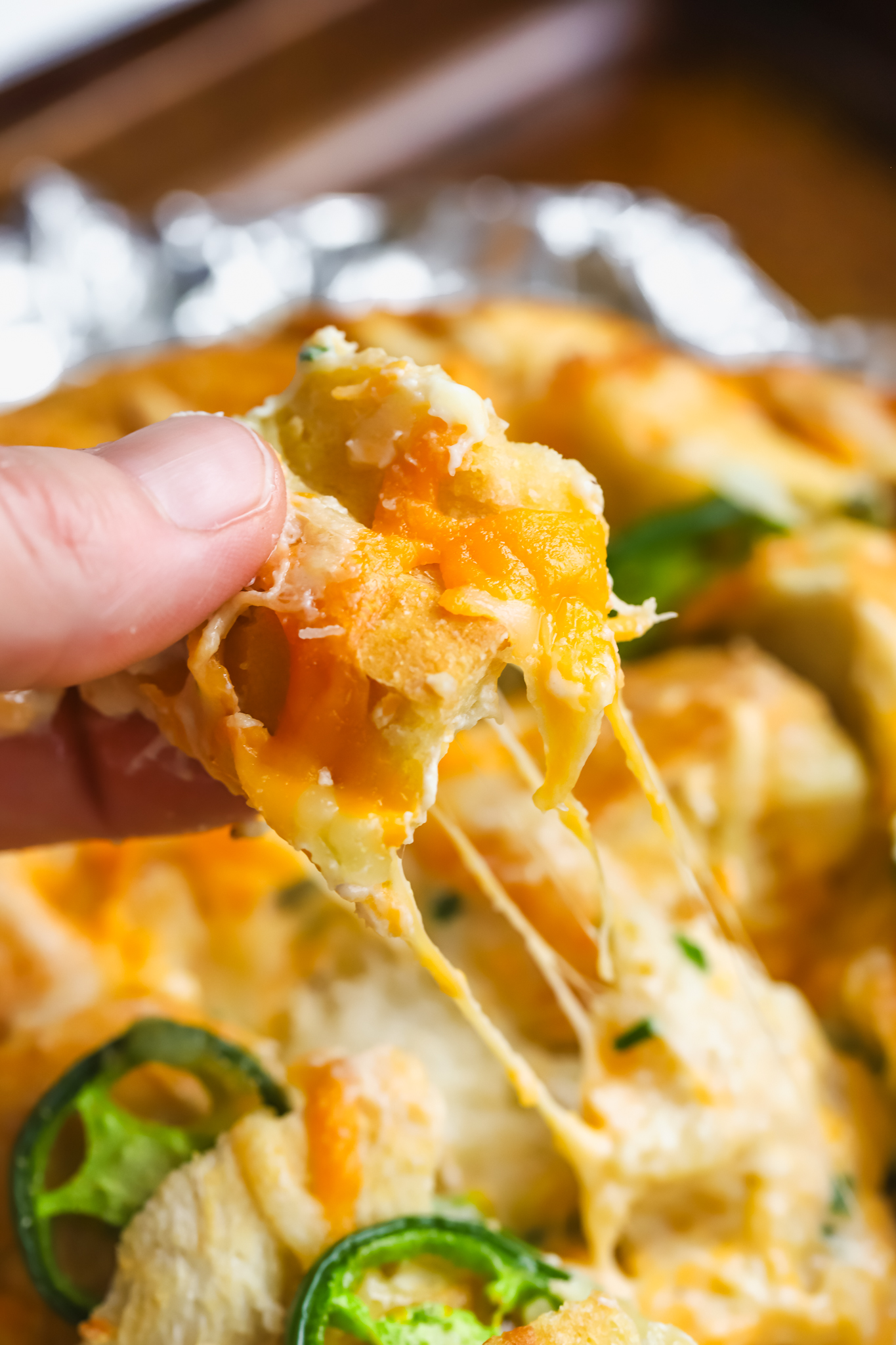 hand pulling piece of cheesy bread 
