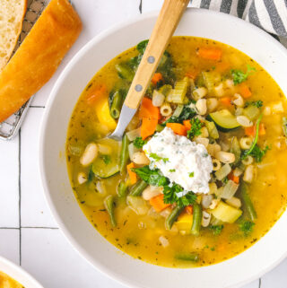 Spring minestrone soup in a bowl topped with basil-lemon ricotta