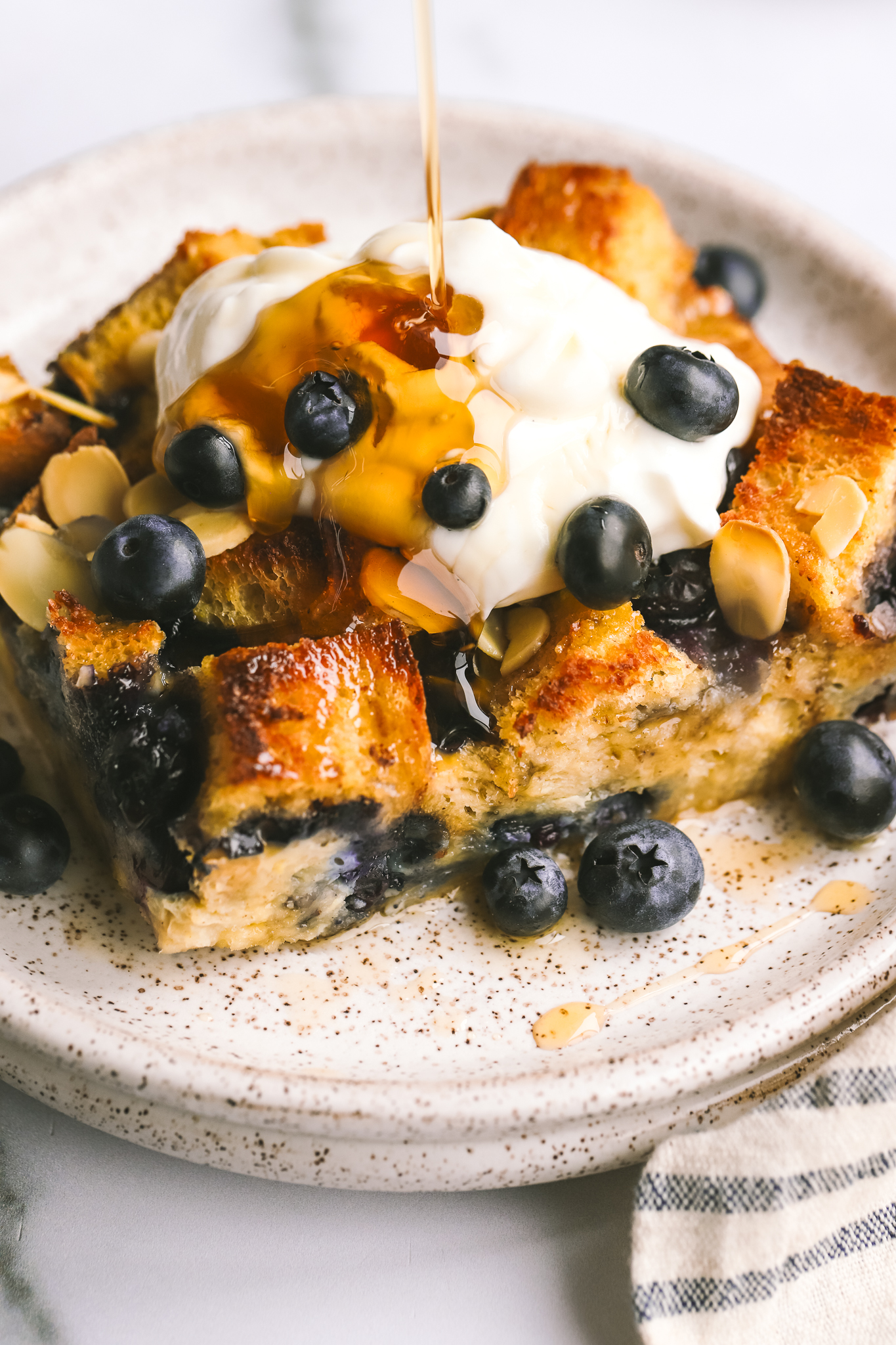 syrup being poured on a piece of blueberry breakfast bake 
