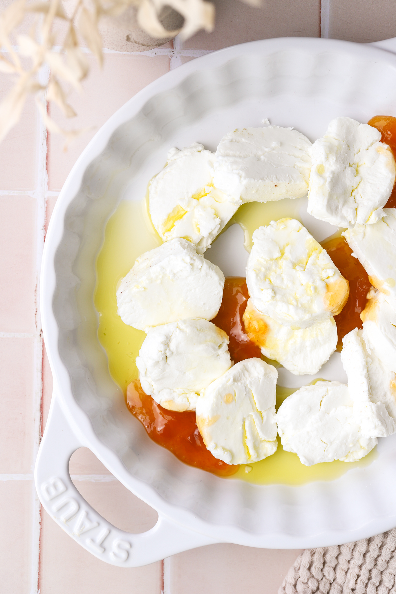rounds of goat cheese in a baking dish with olive oil and apricot jam