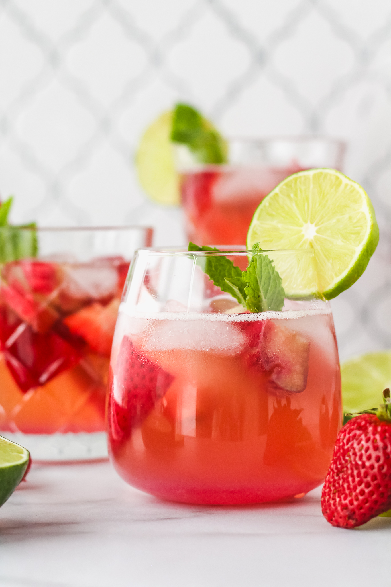 berry rhubarb kombucha sangria in a glass garnished with lime and fresh mint