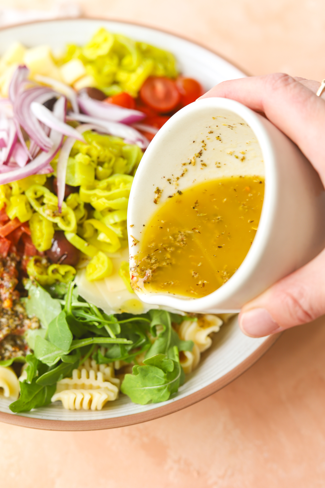 lemon oregano vinaigrette being poured onto a pasta salad