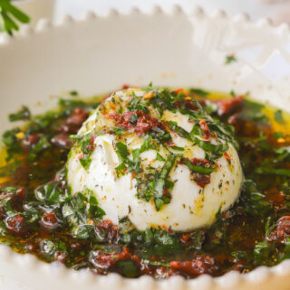 ball of burrata in a bowl drizzle with olive oil and herbs