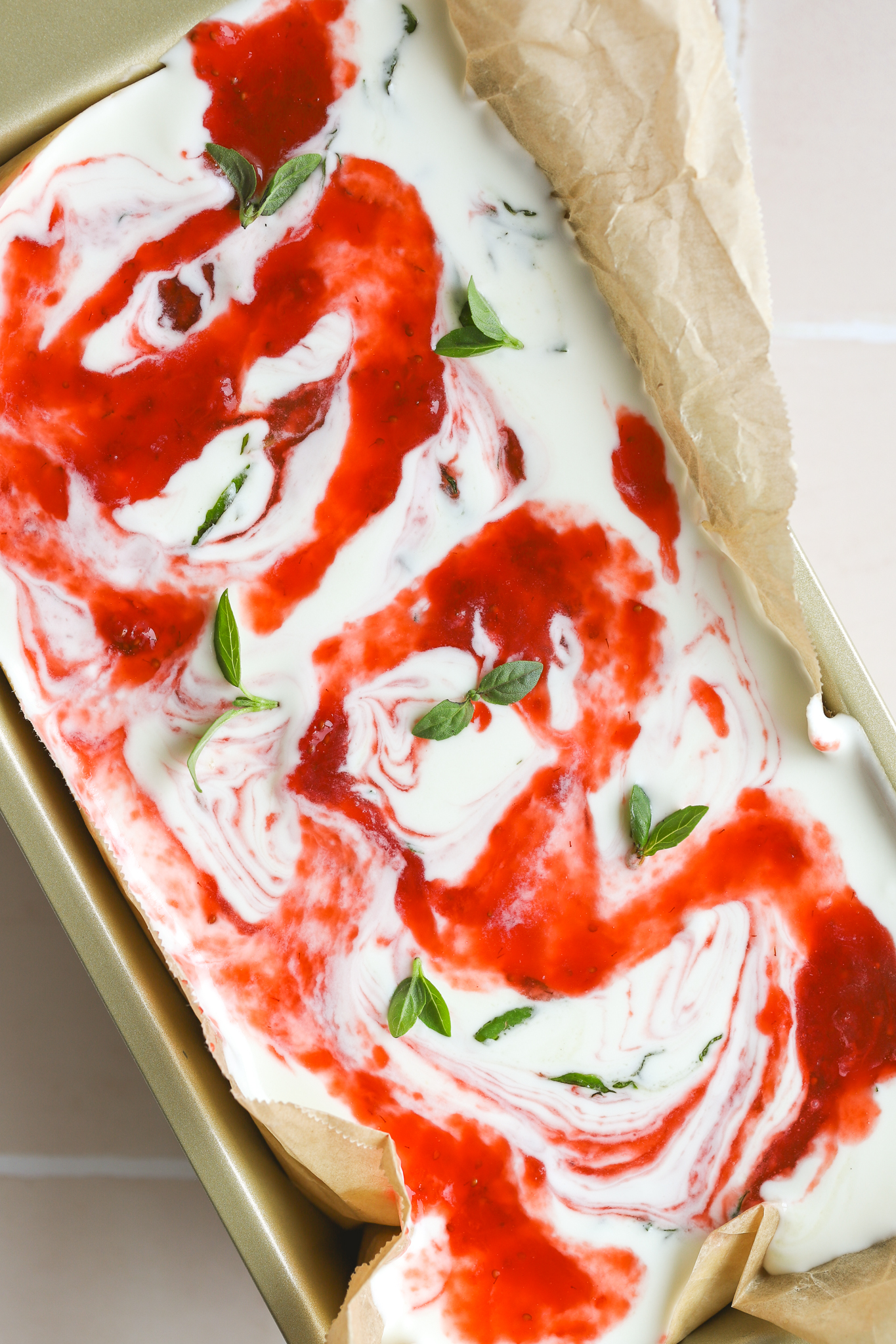 strawberry puree swirled through no churn ice cream in a loaf pan