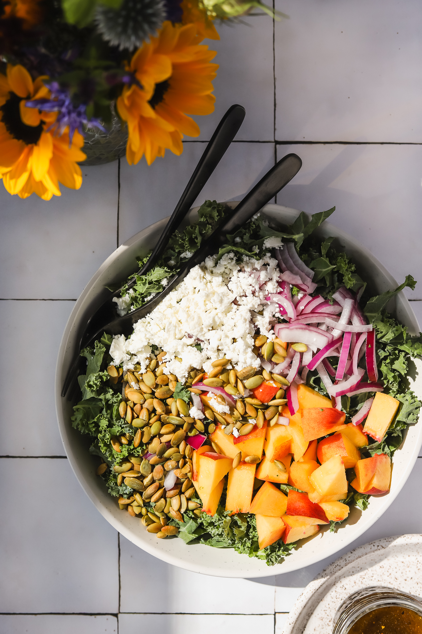 kale and peach salad in a bowl with flowers nearby