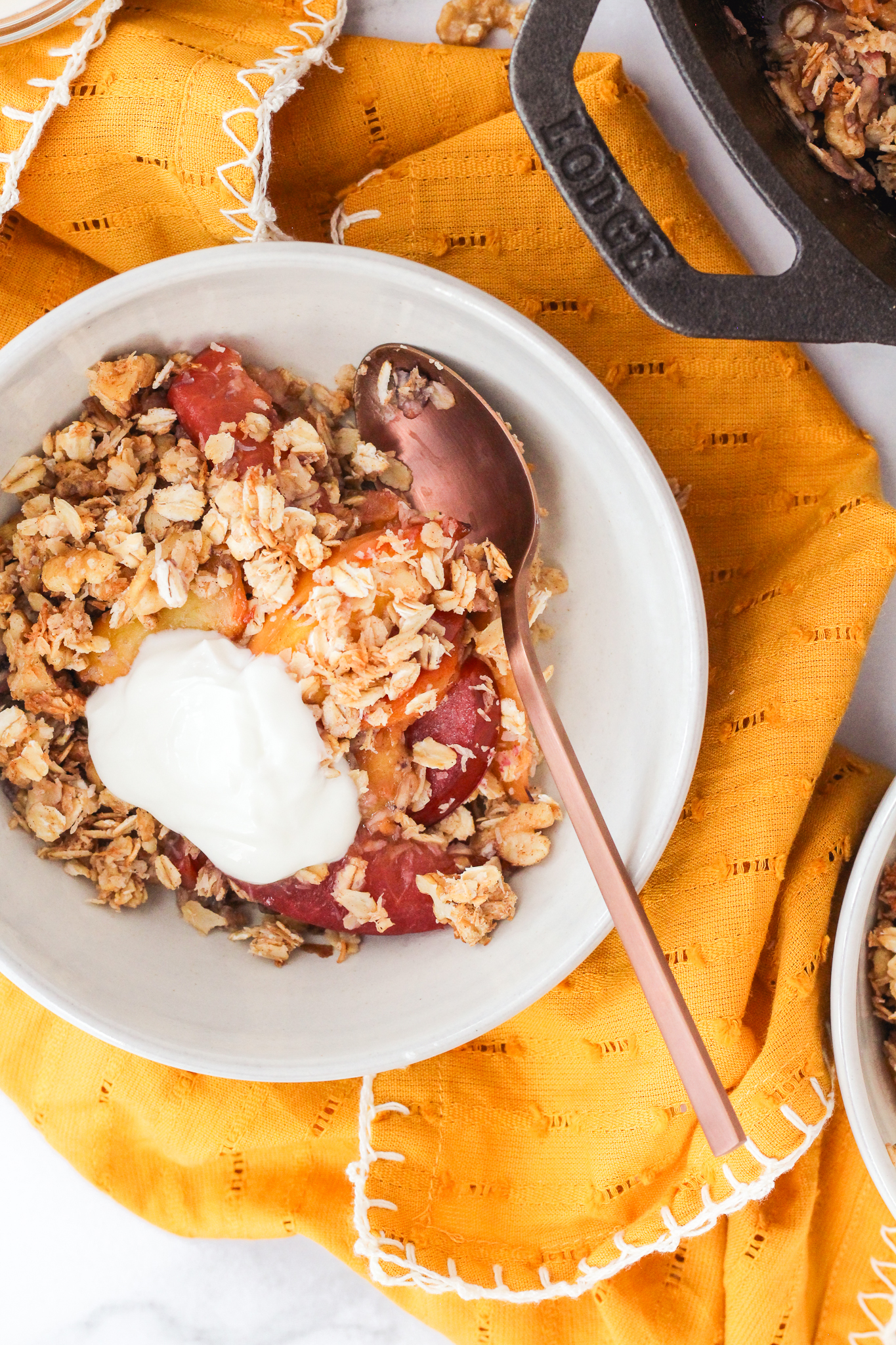 stone fruit breakfast crumble in a bowl topped with yogurt