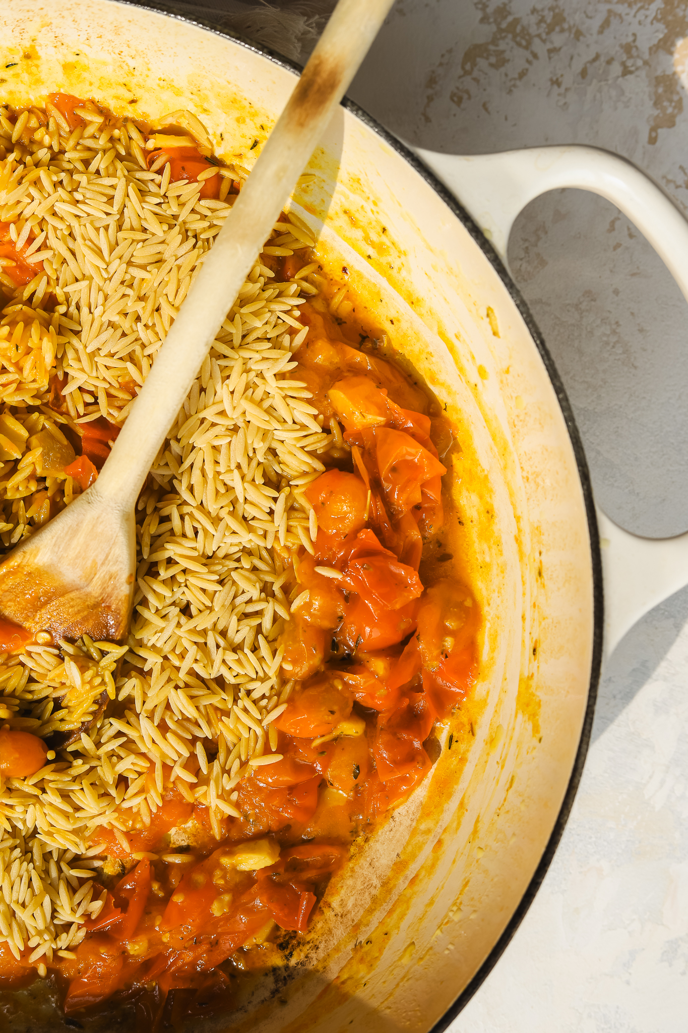 dry orzo pasta and burst tomatoes in a pan