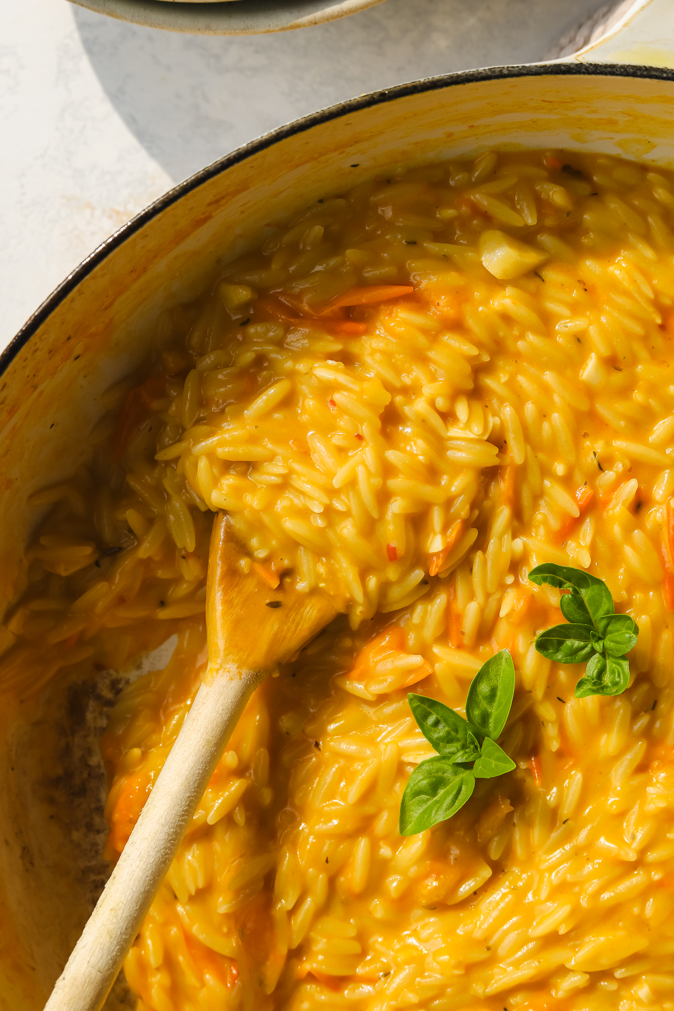 close up of wooden spoon in cooked tomato orzo