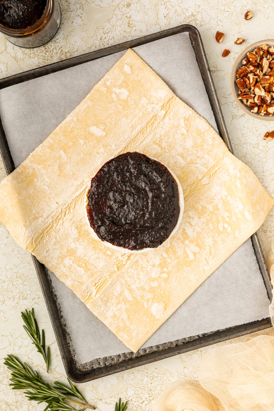 wheel of brie with fig jam on a piece of puff pastry