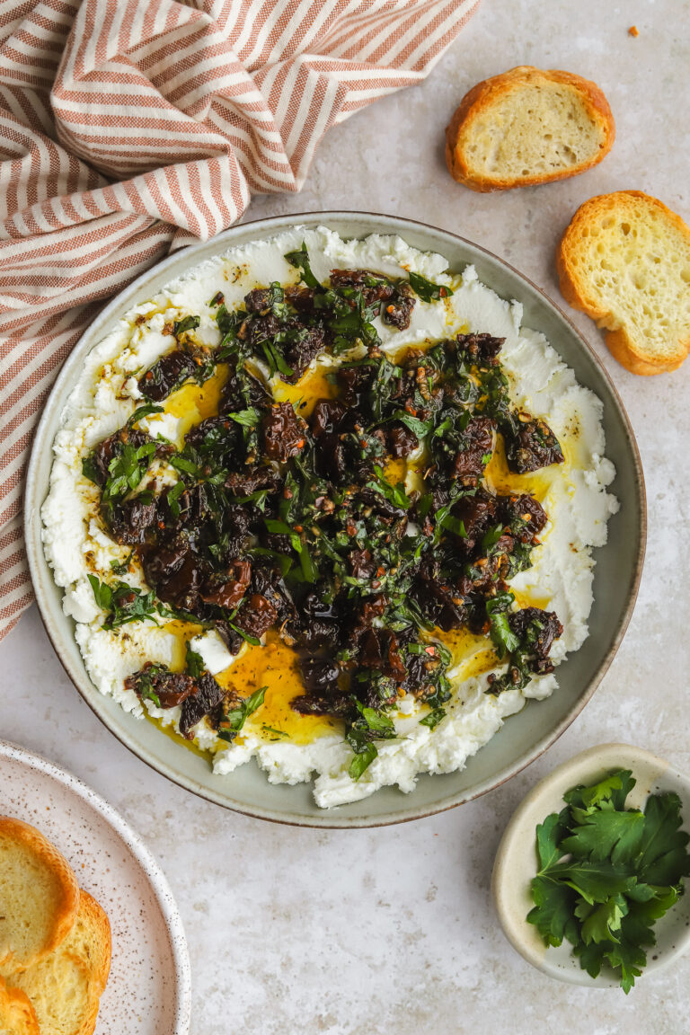marinated goat cheese with sundried tomatoes and fresh herbs in a low bowl