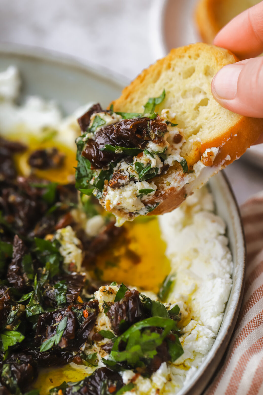 crostini dipped into marinated goat cheese dip