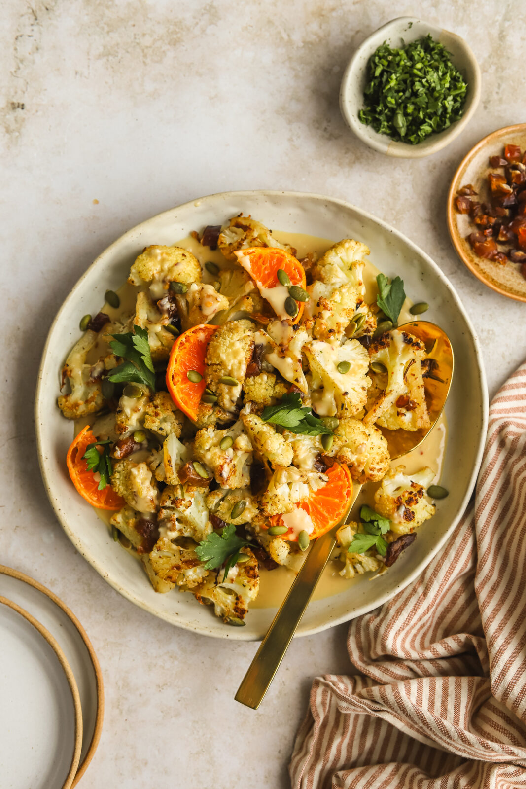 roasted cauliflower in a serving dish with orange tahini sauce