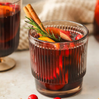 glass of red sangria with oranges, apples, cinnamon stick and rosemary