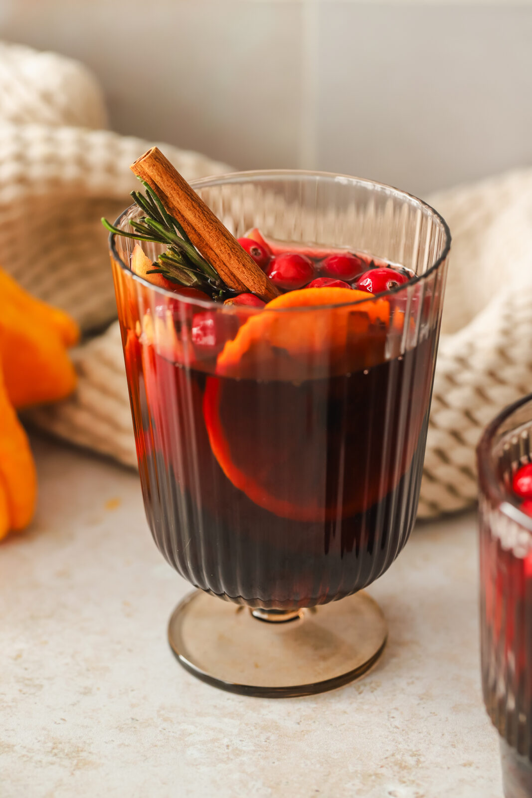 glass of red sangria with oranges, apples, cinnamon stick and rosemary