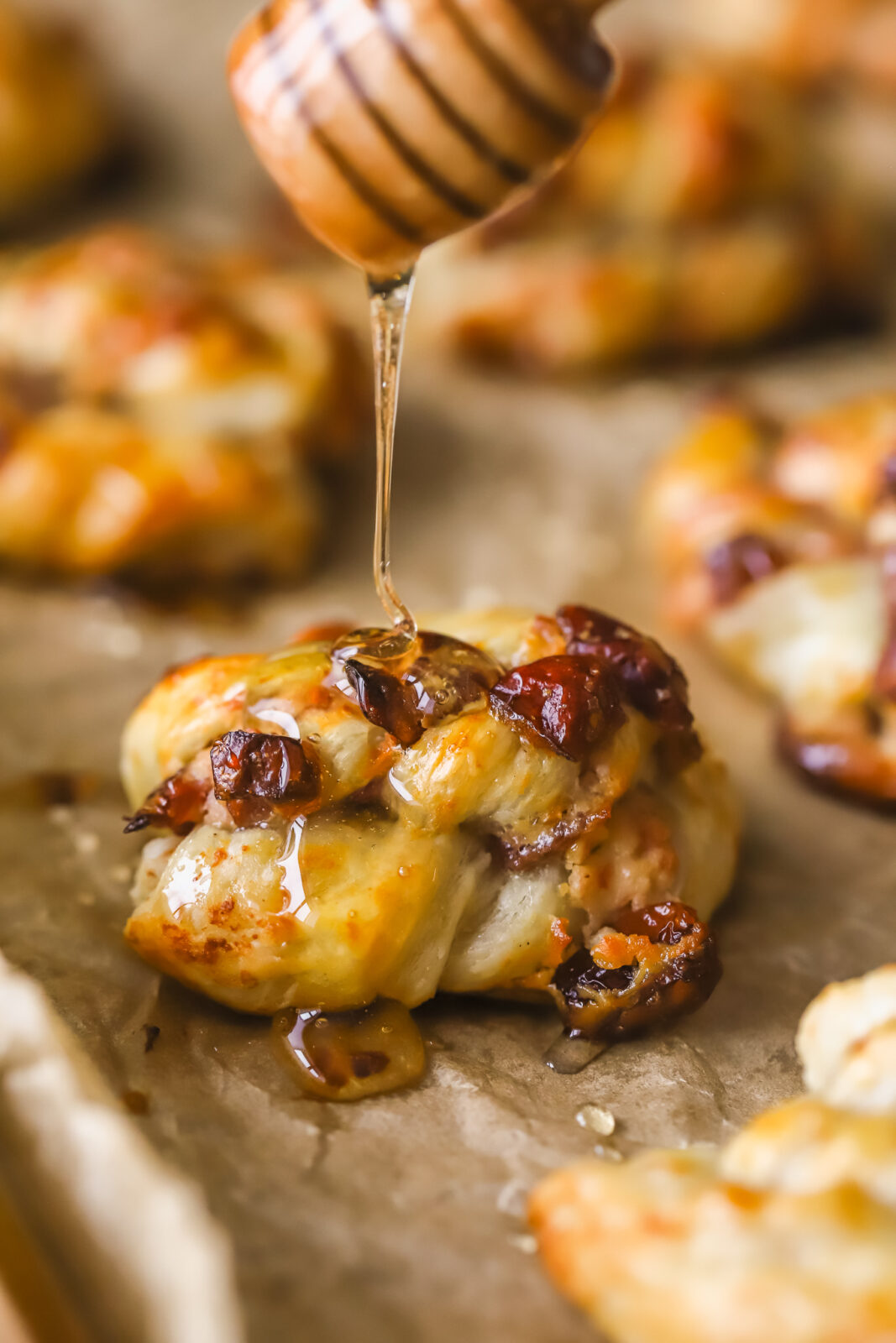 close-up of cranberry goat cheese puff pastry swirl with a honey drizzling onto it