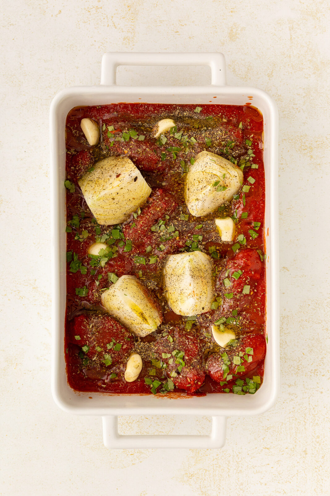 baking dish with onions, garlic, canned tomatoes and seasonings