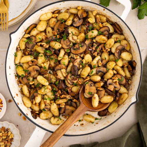 gnocchi side dish with mushrooms, walnuts and parsley in a pan
