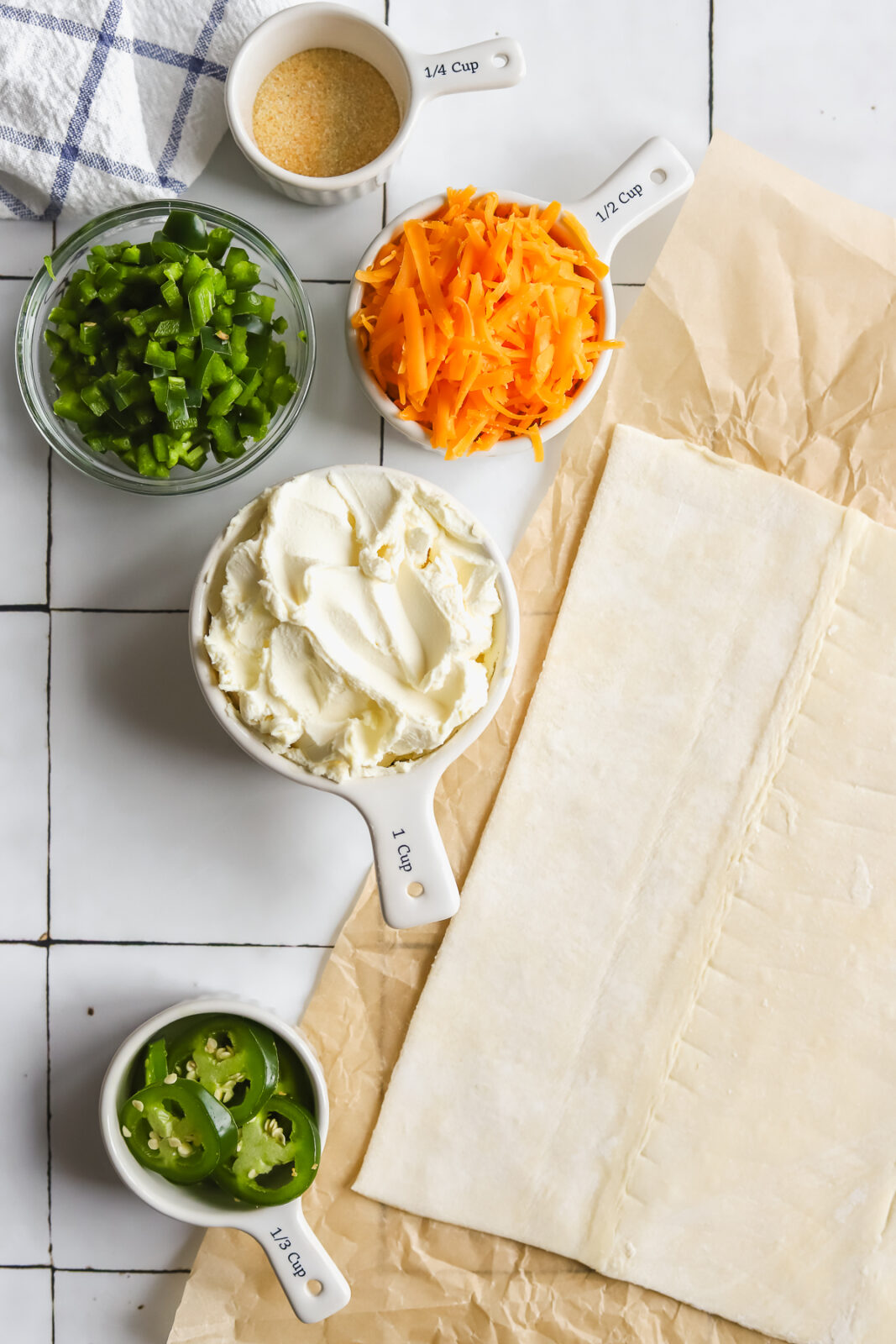 bowls of cream cheese, shredded cheese, jalapenos and a sheet of puff pastry