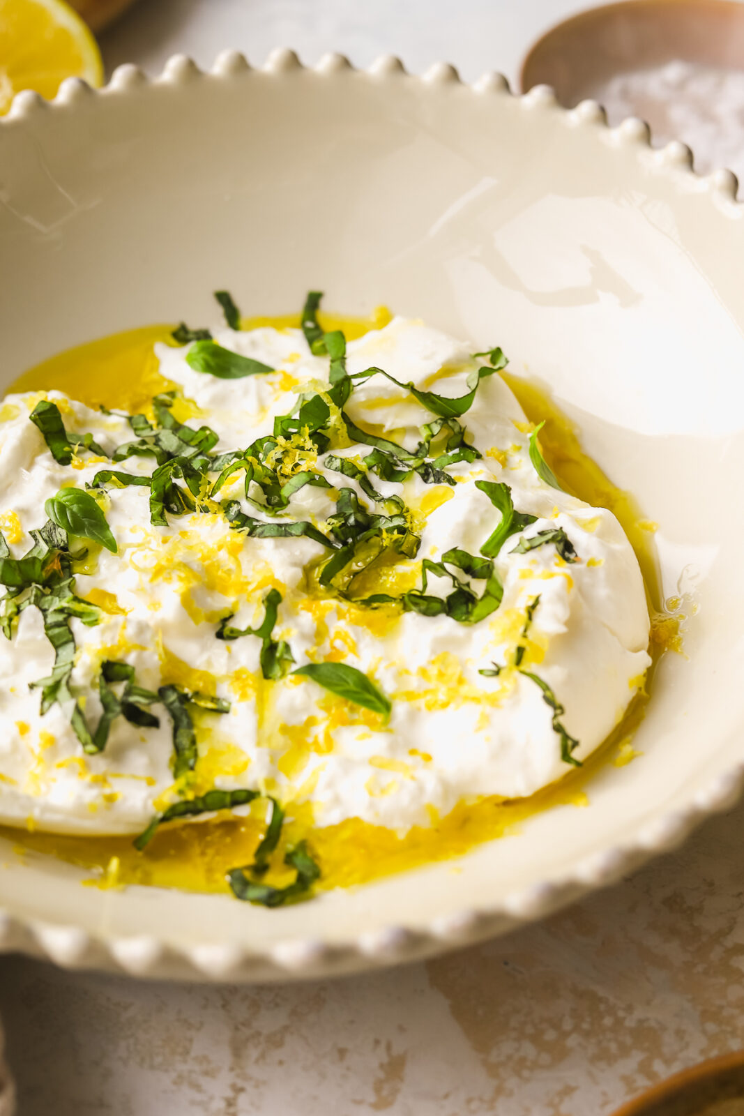 close up of burrata with olive oil, fresh basil and lemon zest